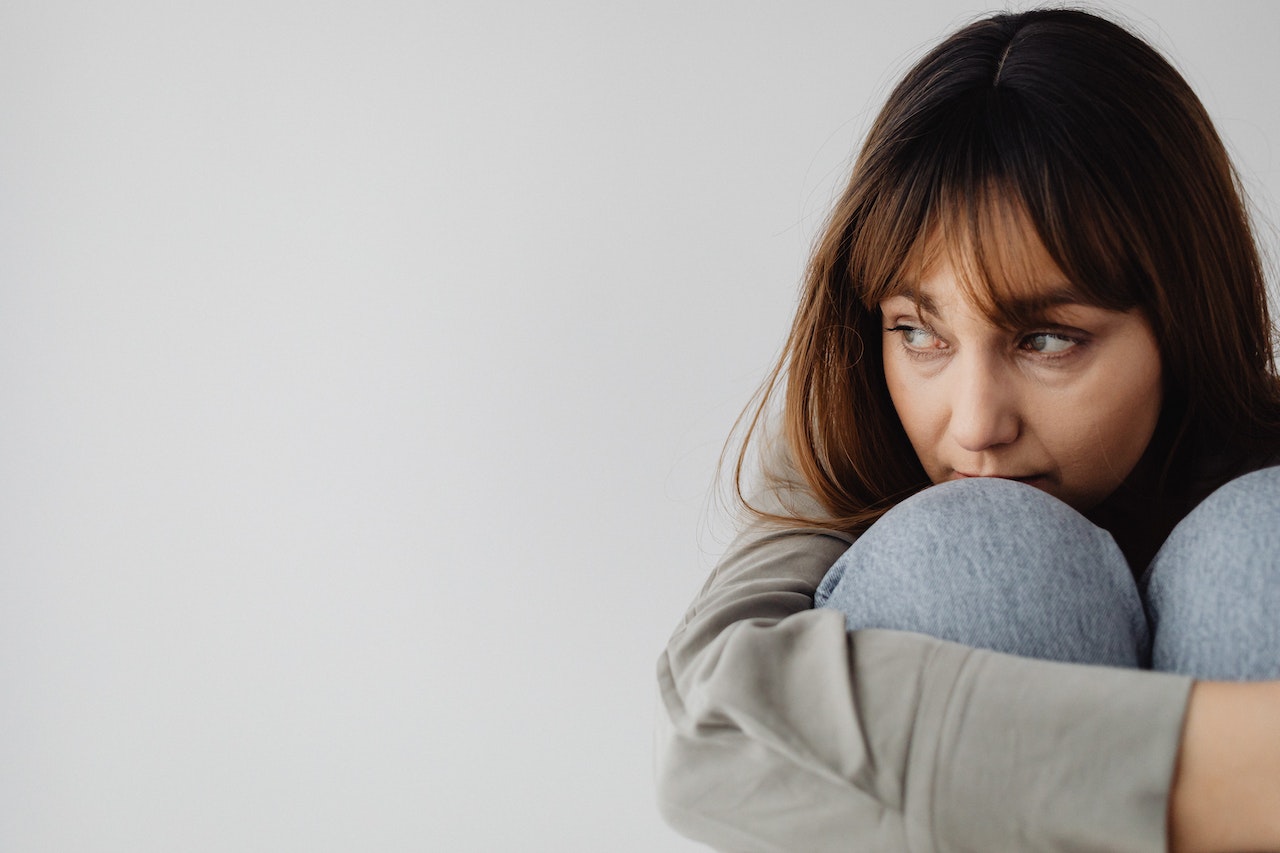 reparent yourself. Woman sitting on the floor with knees hugged into her chest.